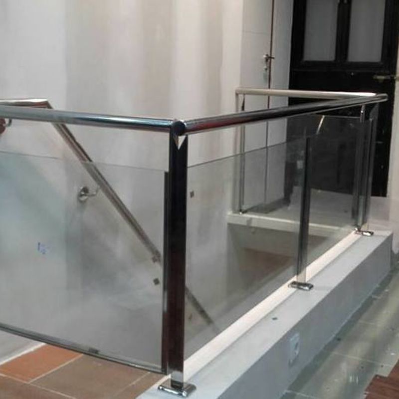 Barandilla de acero inoxidable y vidrio con puerta de acceso a sótano diseñado y montado a medida para local comercial.