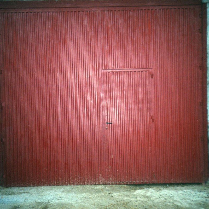 Puerta industrial de dos hojas batientes, con puerta de servicio incorporada