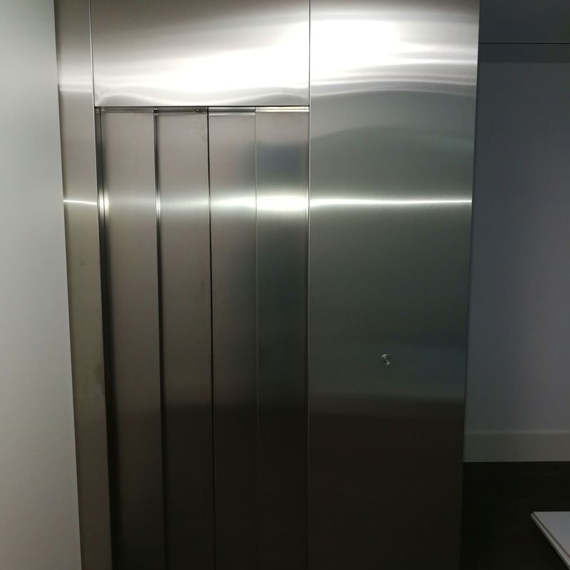 Forros de frente de ascensor fabricado con chapa de acero inoxidable satinado.