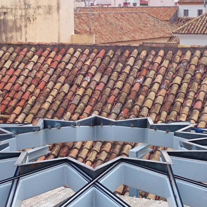 Estructura de acero negro con forma de estrella formando una base totalmente plana para alojar un vidrio con la misma forma diseñado y fabricado a medida  para techo de patio andaluz de palacete 