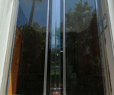 Puerta de acero inoxidable con vidrios de seguridad fabricada a medida.