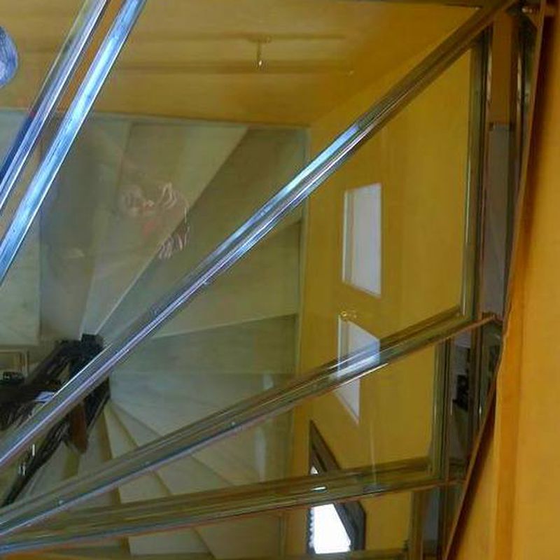 Escalera de acero inoxidable y vidrio con barandilla de acero inoxidable y pasamanos diseñada y fabricada a medida.