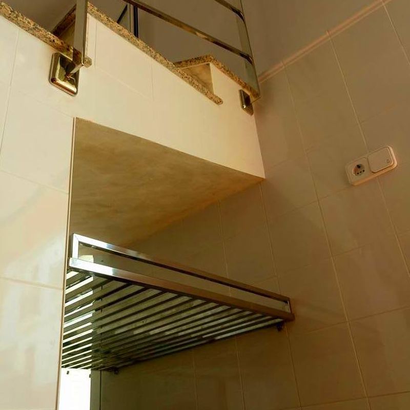 Estantería de acero inoxidable diseñada y fabricada a medida para hueco de escalera de garaje de vivienda particular.