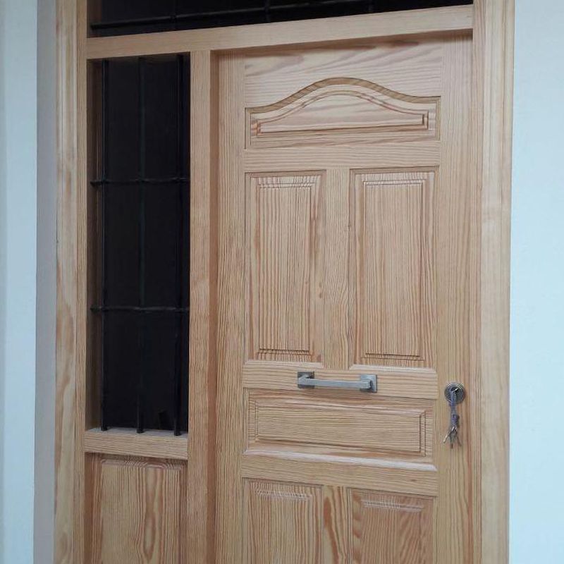 puerta de entrada de pino tea barnizada, con rejas de forja 