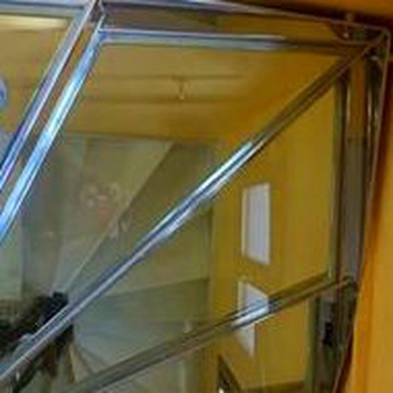 Escalera de acero inoxidable y vidrio con barandilla de acero inoxidable y pasamanos diseñada y fabricada a medida.