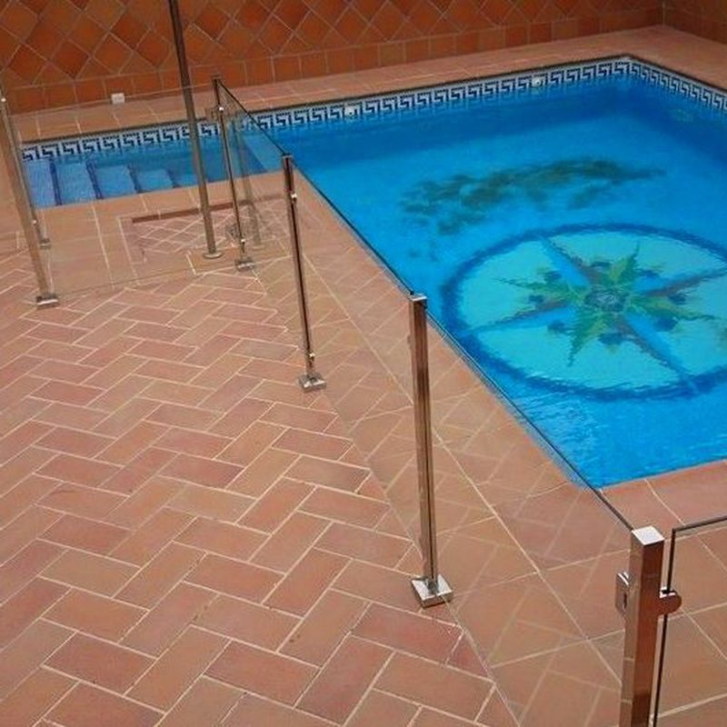 Barandilla de acero inoxidable y vidrio con puerta de acceso a piscina diseñada y fabricada a medida para vivienda particular.